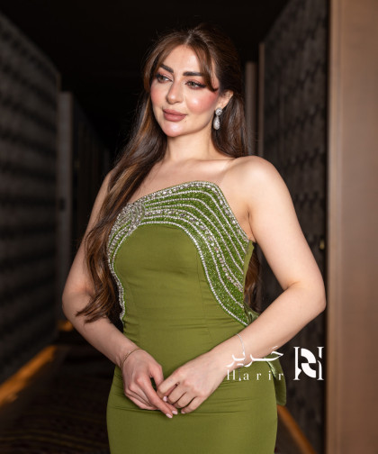 فستان سهرة زيتوني بفتحة صدر غير متناظرة وتفاصيل كريستالية فاخرة
