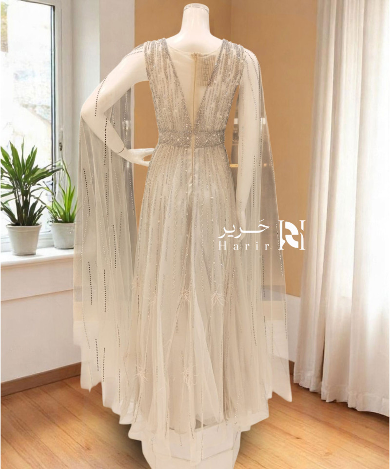 Elegant Off-White Evening Gown with Crystal Embellishments and Flowing Cape Sleeves Elegant Off-White Evening Gown with Crystal Embellishments and Flowing Cape Sleeves