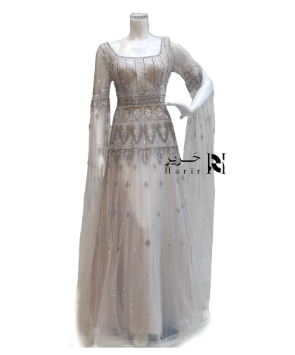 فستان سهرة فضي منقوش بتطريز كريستالي وأكمام طويلة شفافة