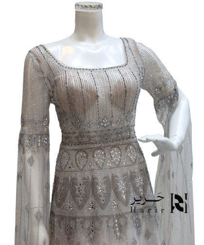 فستان سهرة فضي منقوش بتطريز كريستالي وأكمام طويلة شفافة