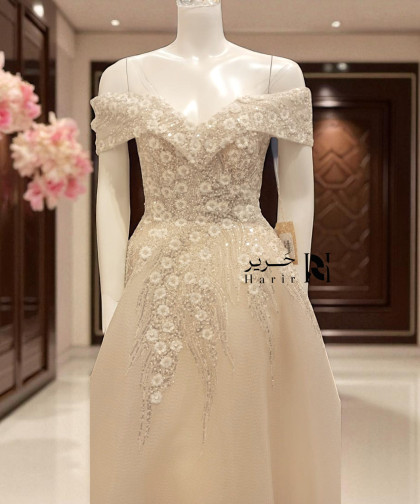 فستان بيج ملكي بأكتاف ساقطة وتطريز زهور لامعة