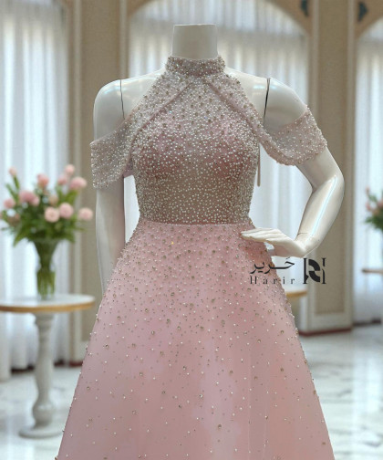 فستان وردي مطرّز بترتر لؤلؤي بقصة مفتوحة على الأكتاف