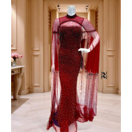 A burgundy gown embellished with shimmering sequins and a luxurious sheer cape.     