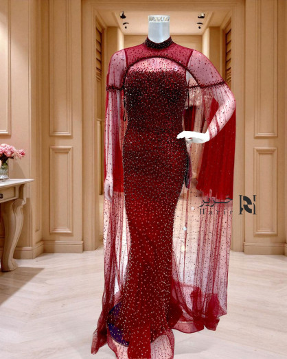 A burgundy gown embellished with shimmering sequins and a luxurious sheer  cape. -
