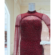 A burgundy gown embellished with shimmering sequins and a luxurious sheer cape.     