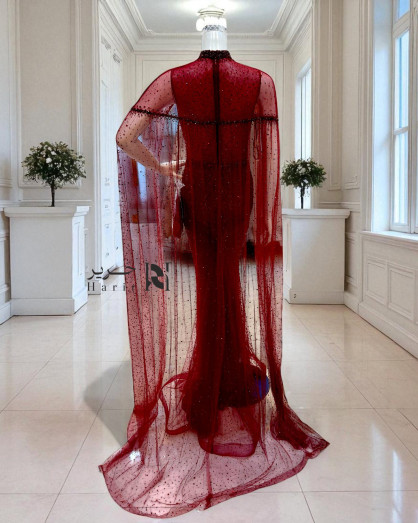 A burgundy gown embellished with shimmering sequins and a luxurious sheer  cape. -