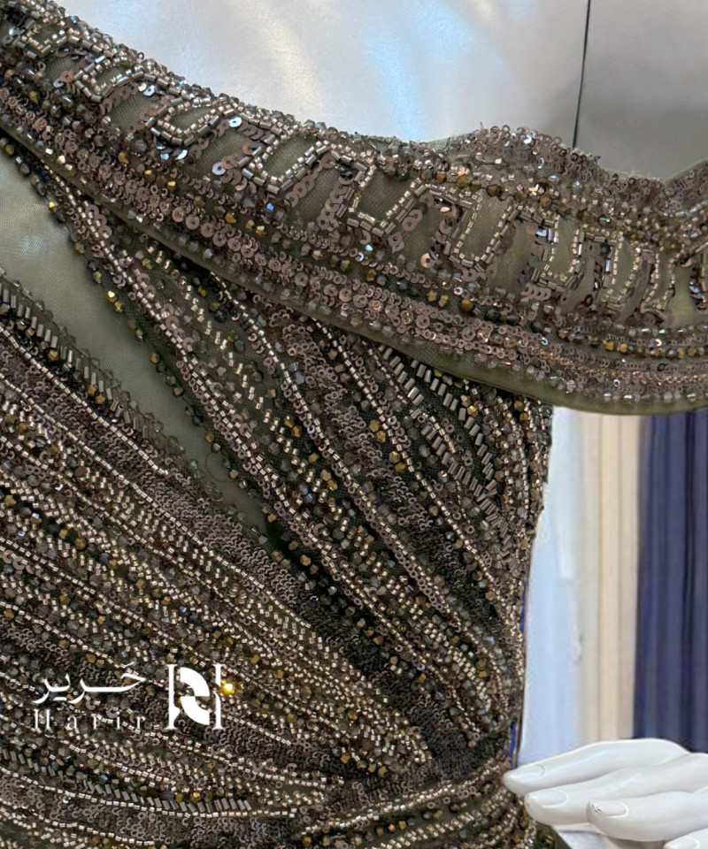 فستان سهرة زيتوني مطرّز بكتف ساقط وتفاصيل لامعة