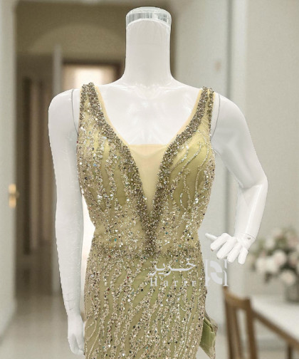 فستان سهرة ذهبي مطرّز بالترتر والريش