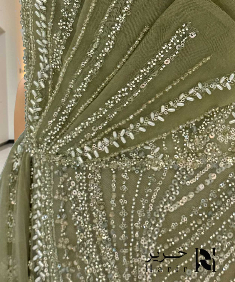 Olive green one-shoulder evening dress with beaded embroidery and side tulle drape.