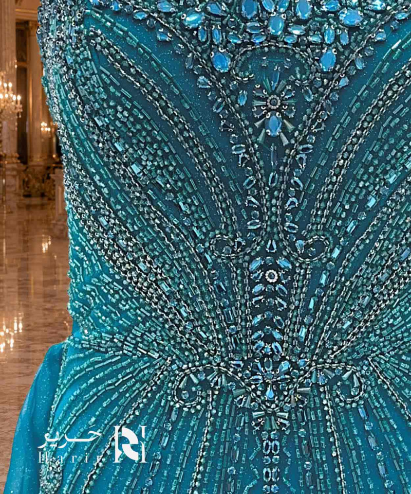 فستان سهرة تركوازي بترولي بقصة حورية وصدر قلب مرصع بالكريستال مع كاب تول جانبي